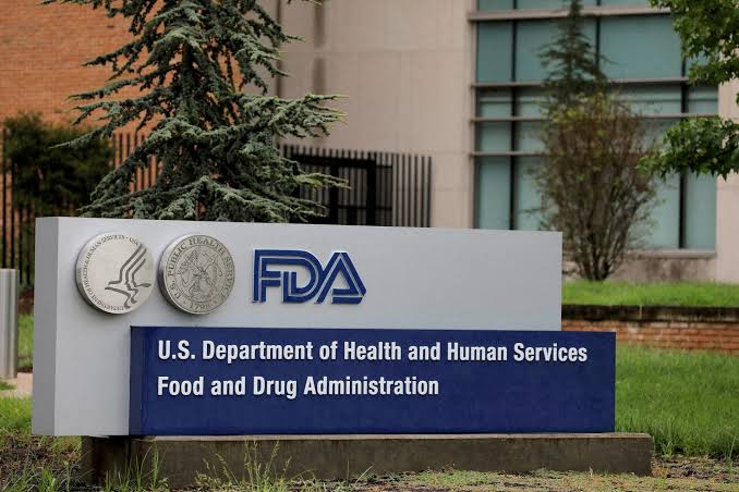 The official entrance sign of the U.S. Food and Drug Administration (FDA) featuring the FDA logo, two government seals, and the agency's name in white text on a blue background.